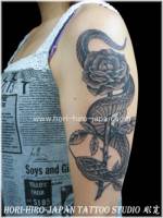 Tatuaje de serpiente enroscada en una rosa en el brazo.