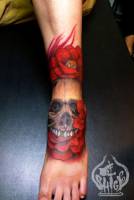 Tatuaje de una calavera a color entre flores rojas