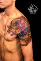Tatuaje de serpiente saliendo entre flores en el hombro