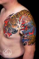 Tatuaje japonés de tigres, con agua y olas. Tatuaje de medio brazo y pecho.