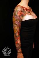 Tatuaje japonés de un dragón y flores, en el brazo de una mujer