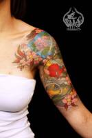 Tatuaje de flores y pájaros en el brazo.