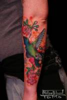 Tatuaje de colibrí y flores en el antebrazo