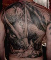 Tatuaje de un dragon comiendose un angel abatido