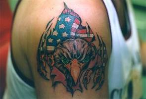 Tatuaje de un águila desgarrando la piel con la bandera americana detrás