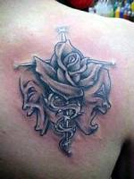Tatuaje de una cruz con una rosa y mascaras