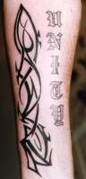 Tatuaje de un tribal en la pierna con un nombre en letras góticas