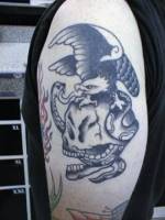 Tatuaje de águila encima de una calavera, luchando contra una serpiente.