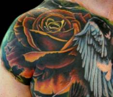 Tatuaje de una rosa con alas y sombras de pájaros