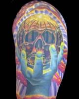 Tatuaje de una mano agarrando una bola de cristal con una calavera