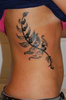 Tatuaje de una planta en el costado de una mujer