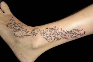 Tatuaje de una frase en el pie y pierna