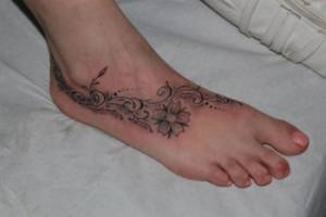 Tatuaje de flores y plantas en el pie