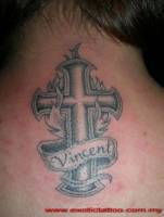 Tatuaje de una cruz en llamas con un nombre en ella
