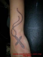 Tatuaje de una cruz colgada de una cadena