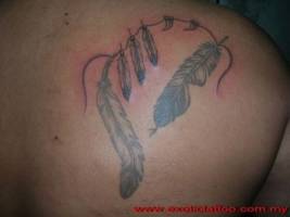 Tatuaje de un collar de plumas y colmillos