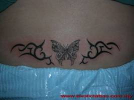 Tatuaje de una mariposa entre dos tribales