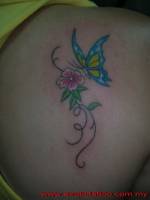 Tatuaje de una mariposa en color volando hacia una flor