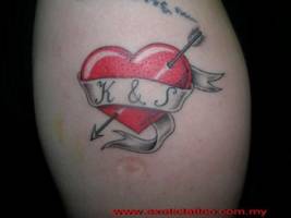 Tatuaje de un corazón atravesado por una flecha y una etiqueta con unas iniciales