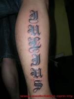 Tatuaje de un nombre de letras góticas en la pierna 