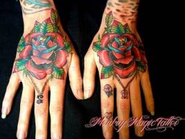 Tatuaje de unas flores con colgantes en la mano