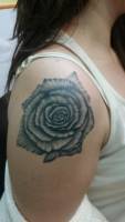 Tatuaje de una rosa en blanco y negro en el hombro de una chica