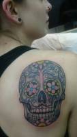 Tatuaje de una calavera de azúcar a color en la espalda de una mujer