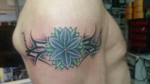 Tattoo a color de un tribal con una flor en medio