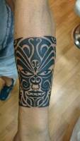 Tattoo de una mascara maorí formando un brazalete
