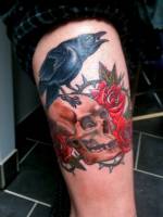 Tattoo de un cuervo posado en una calavera con rosas