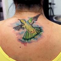 Tatuaje de un pájaro volando debajo de la nuca de una chica