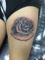 Tatuaje de una rosa en la pierna, con una frase debajo