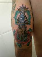 Tatuaje de una torre con el ojo que todo lo ve en la cima y una corona
