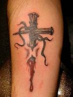 Tatuaje de una afilada cruz de madera atravesando piel