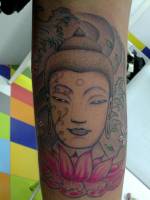 Tatuaje de una cabeza de buda entre olas y encima de una flor de loto