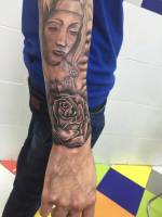 Rosa y virgen tatuadas en el antebrazo
