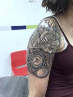 Rosas y reloj tatuados en el brazo de una chica