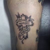 Tatuaje de una cruz y la frase In memory of my enemies