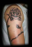 Tatuaje de una rosa enroscada en el brazo