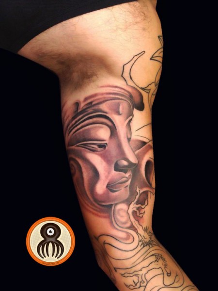 Tatuaje de la cara de un Buda en el bicepss