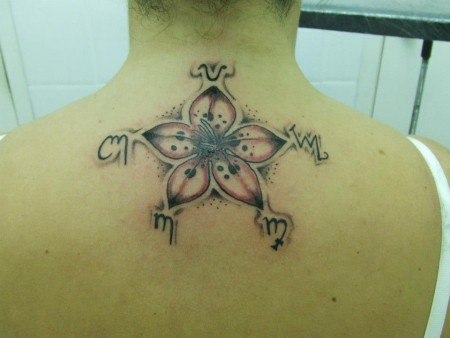 Tatuaje de una flor con un simbolo al terminal cada pétalo