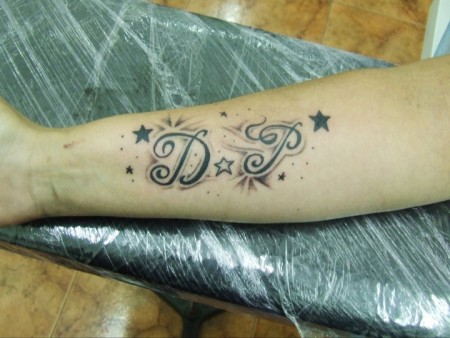 Tatuaje de unas iniciales en un fondo con estrellas