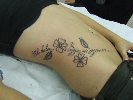 Tatuaje de una frase con unas flores para mujer