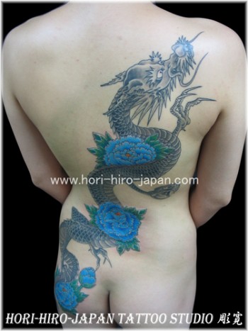 Tatuaje de un dragon japonés atravesando la espalda con flores
