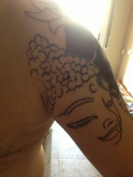 Tatuaje de una cabeza de buddha en el brazo