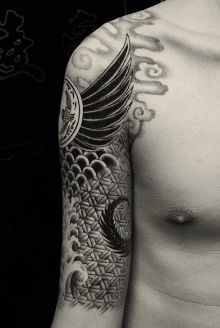 Tatuaje de una armadura en el brazo, con olas y alas