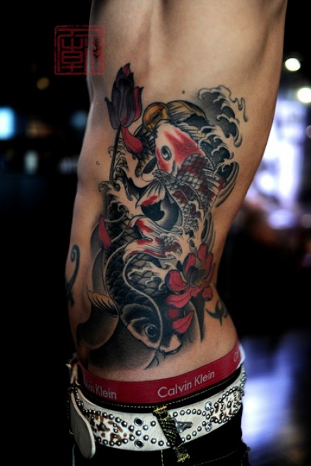 Tatuaje de una carpa subiendo por la espalda
