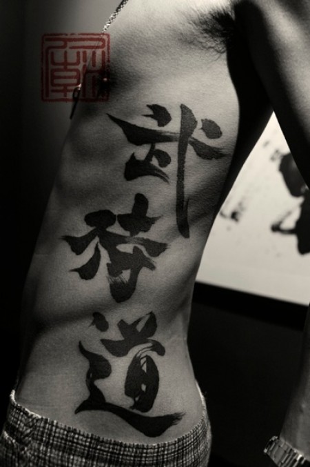 Tatuaje de unos kanjis a pincel en todo el costado