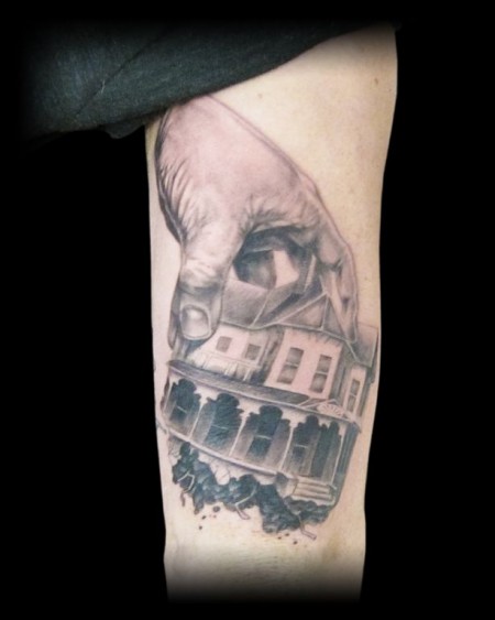 Tatuaje de una mano inmensa agarrando una casa