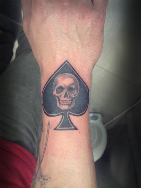 Tatuaje de un as de picas con una calavera